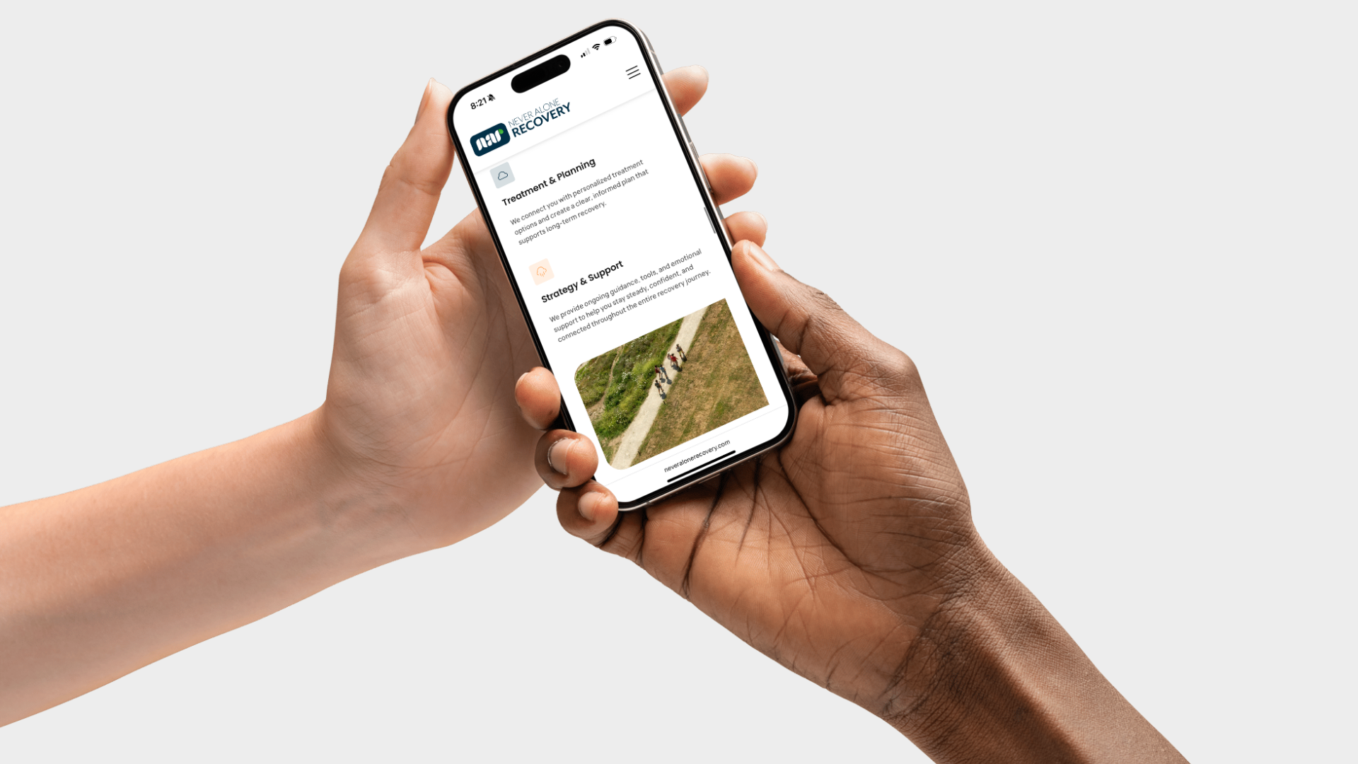 Two hands holding an iPhone showing the redesigned Never Alone Recovery path to healing section
